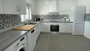 A modern kitchen with white cabinets, a microwave, a toaster, and a dishwasher. - Miamar II House in Chiclana (Chiclana)