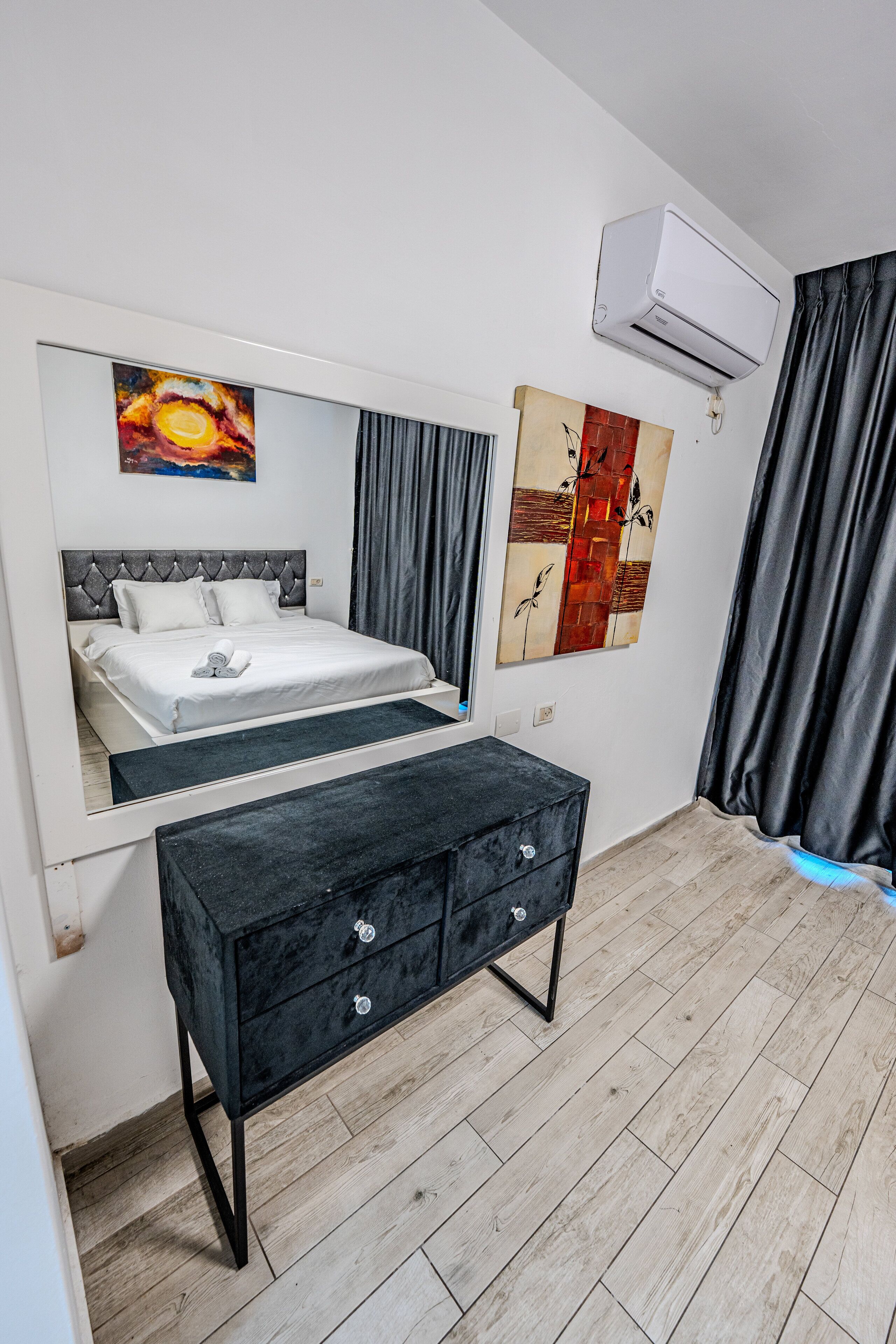 Ein Schlafzimmer mit Bett, Schminktisch, Spiegel und Bildern an den Wänden.