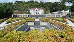 Ein formaler Garten mit einem zentralen Weg, der zu einem weißen Gebäude mit rotem Dach führt.
