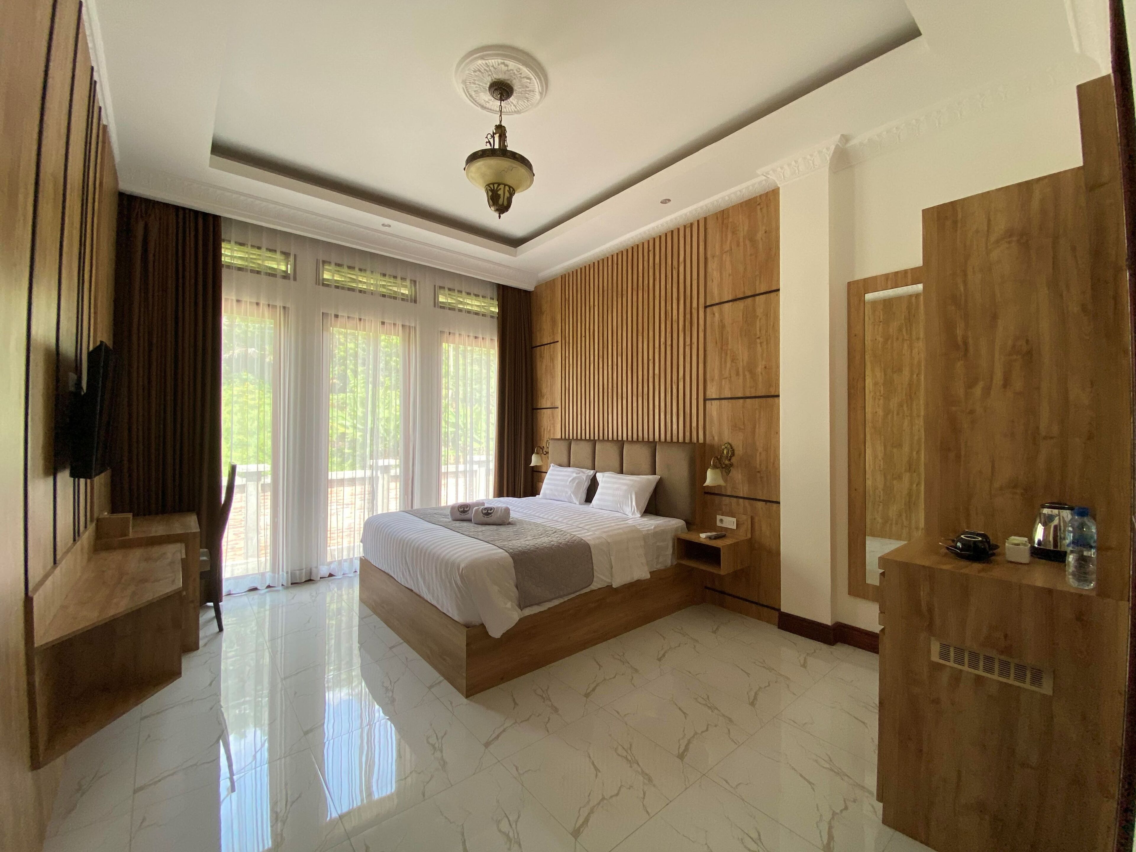 Un dormitorio amplio con una cama grande, paneles de madera, una lámpara en el techo y un armario.