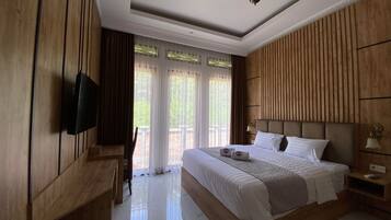 A hotel room with a large bed, wooden paneling, a flat-screen TV, and a balcony with curtains.