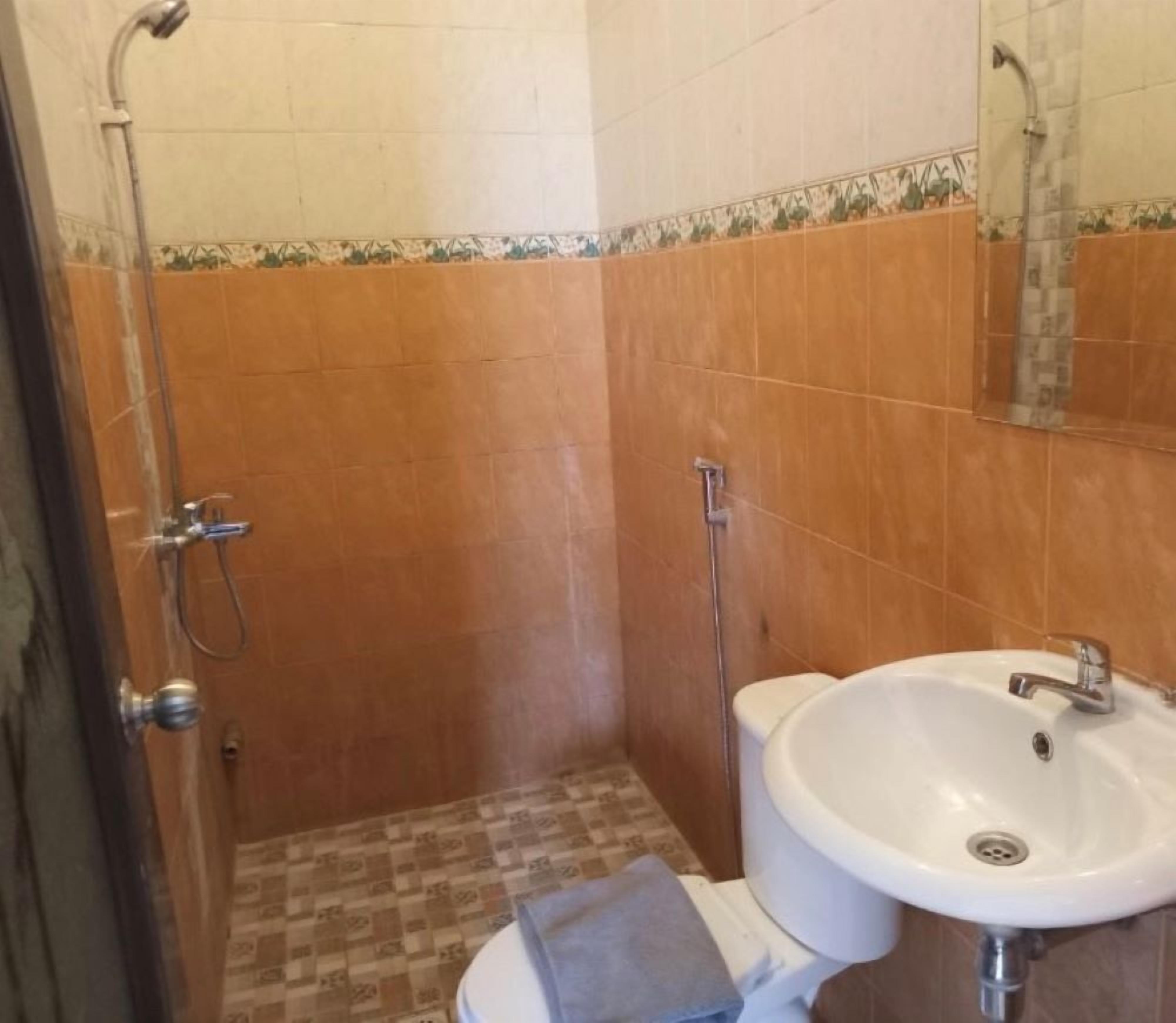 Een badkamer met douche, toilet en wastafel.
