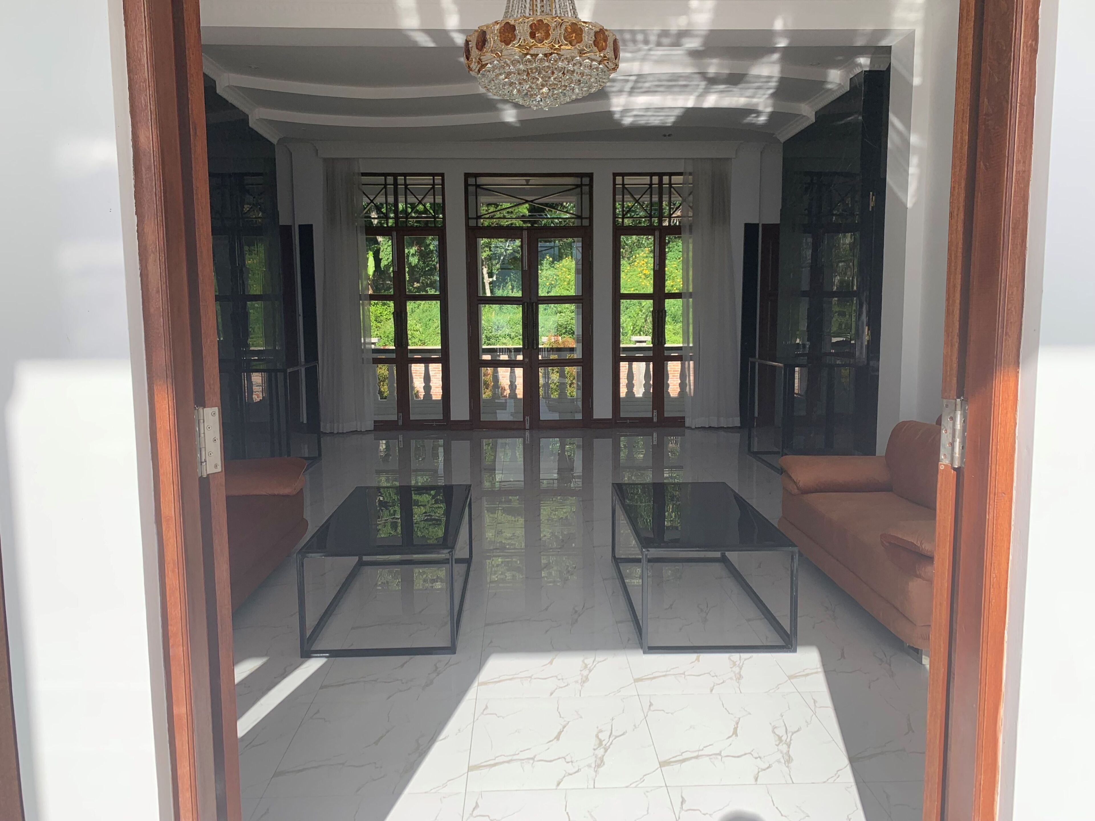 A spacious room with a large window, a chandelier, and a sofa.