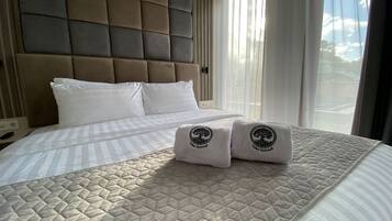 A hotel room with a large bed, a headboard, and two towels with a logo.