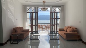 Ein geräumiges Wohnzimmer mit zwei Sofas, einem Glastisch und Meerblick durch große Fenster.