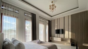 Ein modernes Schlafzimmer mit einem großen Bett, einem flachbildfernseher an der Wand und einer Kristallleuchtre.