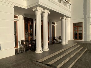 Un bâtiment doté de colonnes blanches, d’un balcon et d’un escalier menant à l’entrée.