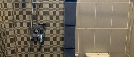 A bathroom with a checkered tile wall, a shower, a toilet, and a towel rack.