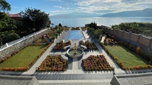Ein angelegter Garten mit einem zentralen Brunnen, einem Pool und Blick auf das Meer.