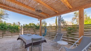 An outdoor patio with a table and chairs, a pergola overhead, and a view of greenery and trees. - Cava Li Santi Residence - Villa La Cava | Appartamento Superior (Santa Caterina)
