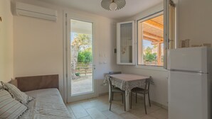 A compact kitchen with a dining table, a refrigerator, and a window overlooking a garden. - Cava Li Santi Residence - Villa La Cava | Appartamento Superior (Santa Caterina)