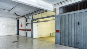 En stilren hall i industriell stil med betongväggar, ett klinkergolv och en stor metalldörr.