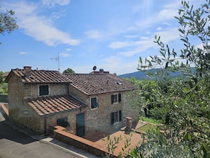 Una casa in pietra con tetto in tegole, un camino e un piccolo giardino.