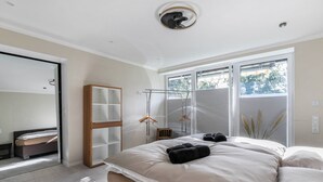 Een slaapkamer met een bed, een kledingkast, een spiegel en een raam met jaloezieën.