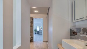 Een moderne badkamer met een groot wastafel, een houten aanrechtblad en een achterwand van steen.