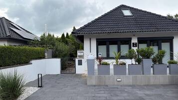 A modern house with a tiled roof, a gated entrance, and potted plants.