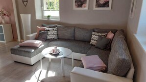 A modern living room with a sectional sofa, a small coffee table, and a potted plant. - Holiday Apartment "Fewo 2 - Osterberg" with Private Terrace, Shared Garden & Wi-Fi (Liebenau)