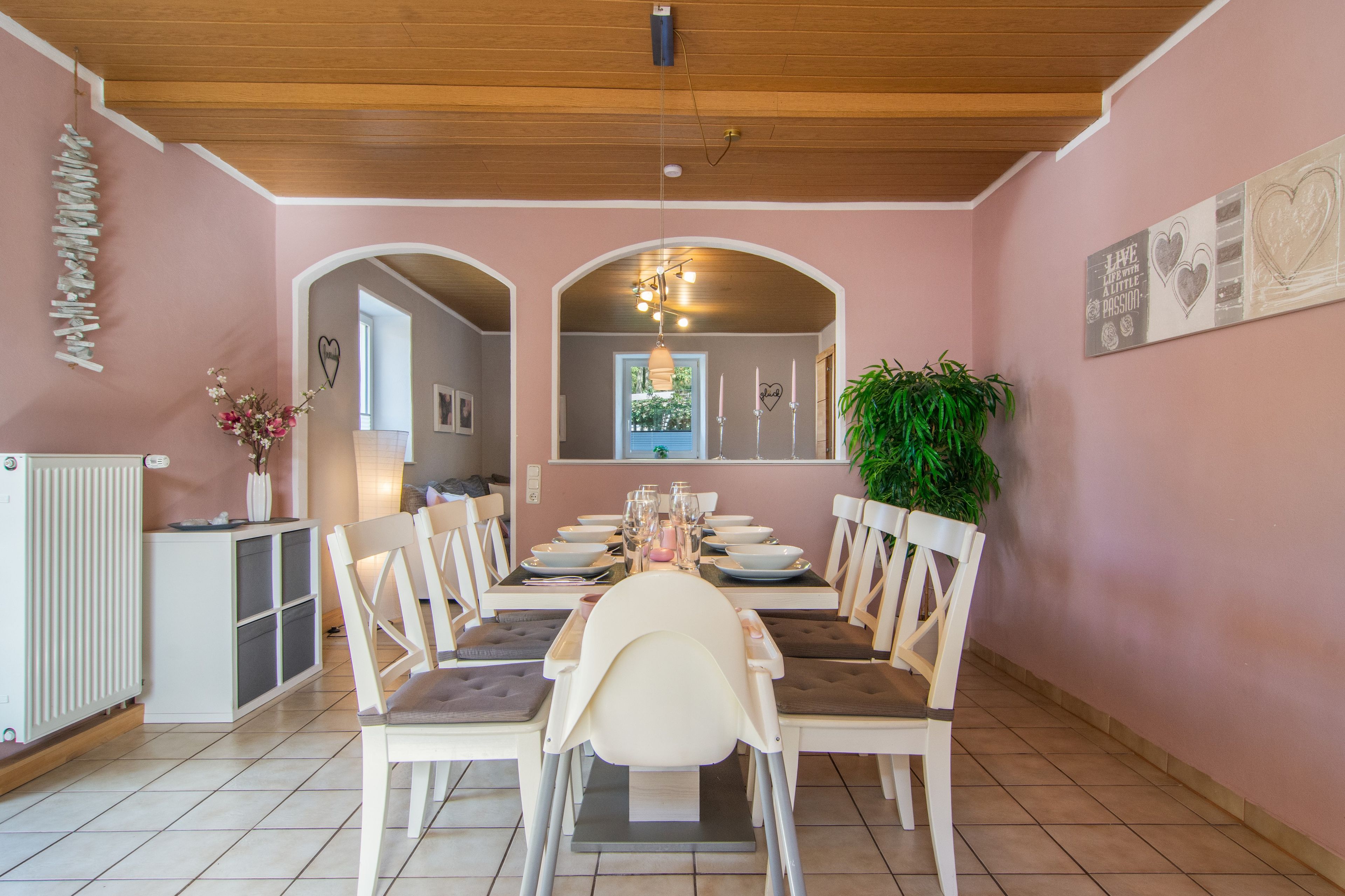 A dining area with a long table set for four, surrounded by chairs.