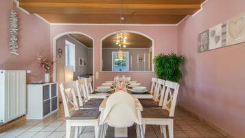 A dining area with a long table set for four, surrounded by chairs.