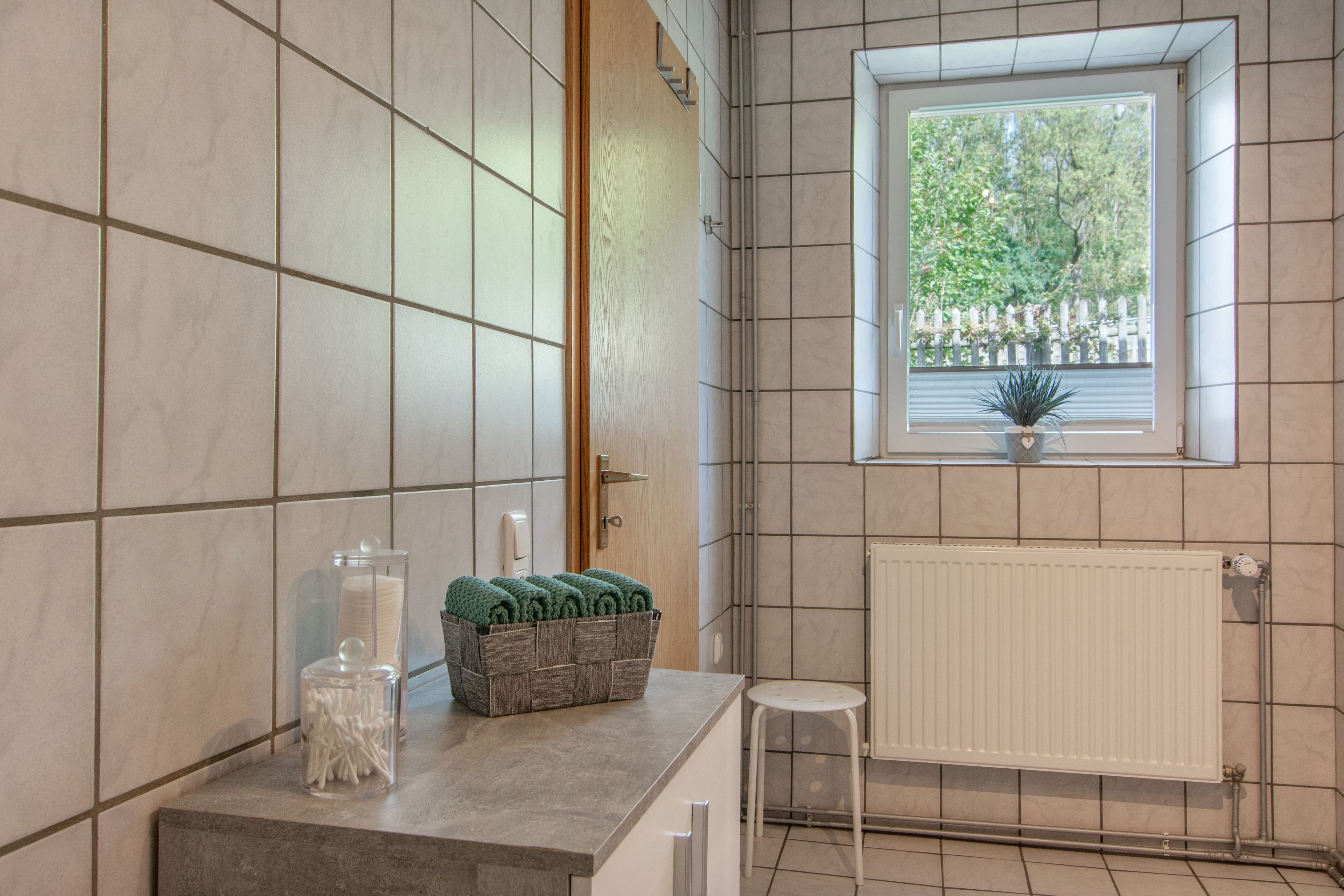 A bathroom with a window, a radiator, and a towel rack.