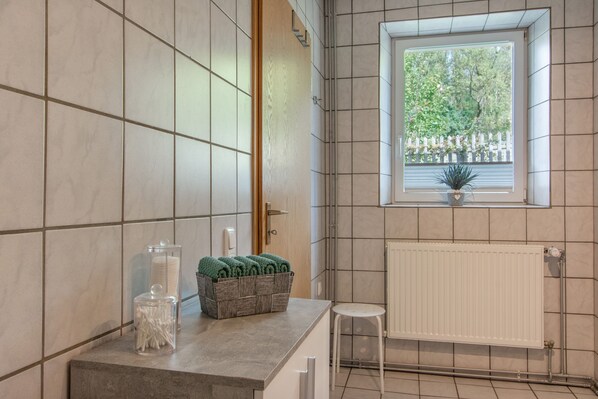 Une salle de bain avec une fenêtre, un radiateur et un porte-serviettes.