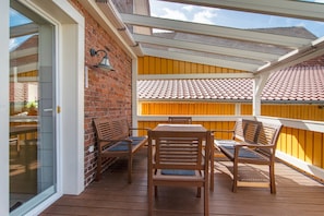 Une terrasse extérieure avec un mur en briques, des meubles en bois et une porte en verre.
