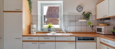 A modern kitchen with a window, a clock, and a microwave.