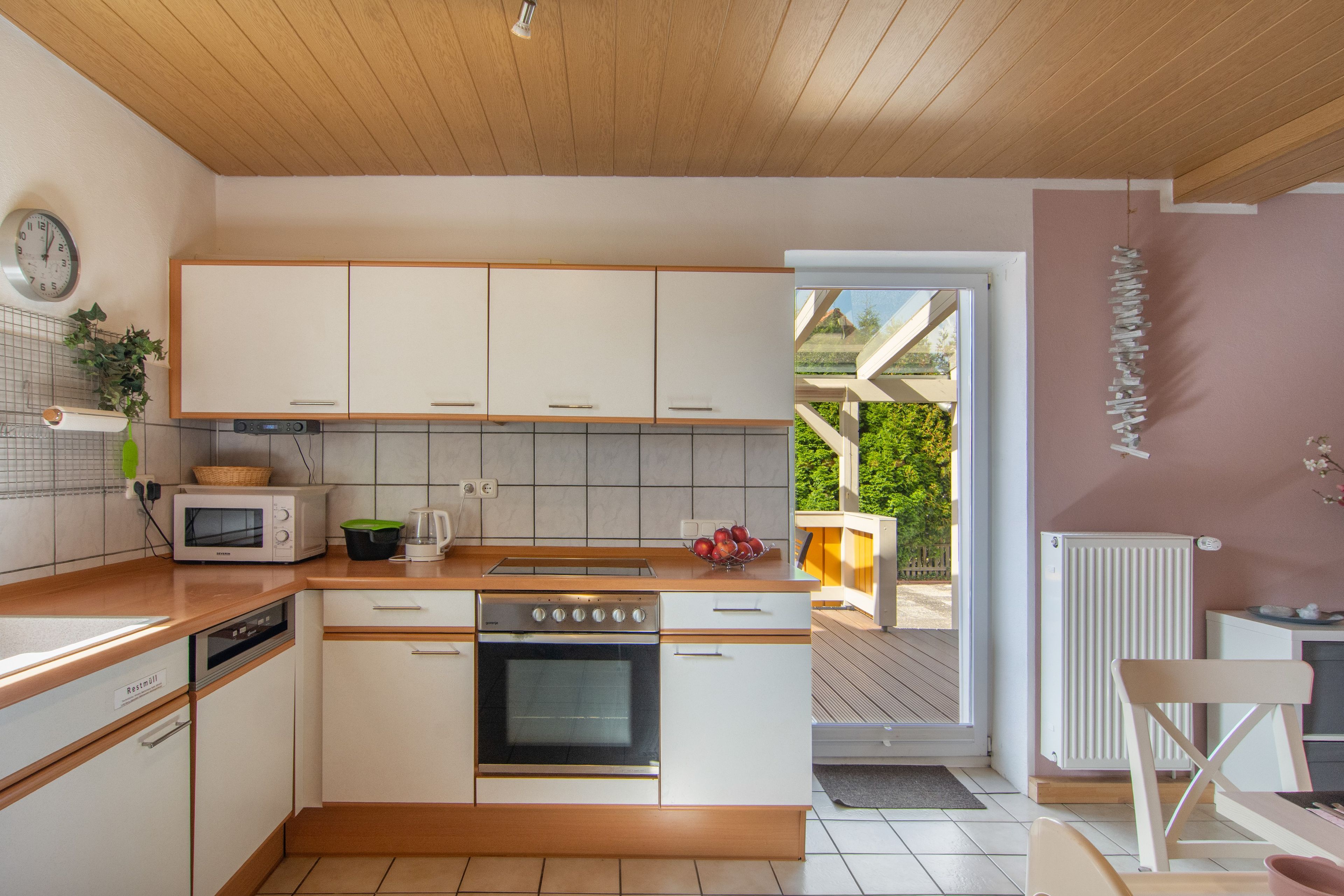 Een moderne keuken met witte kasten, een ingebouwde oven, een magnetron en een spoelbak.