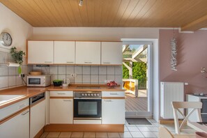 Une cuisine moderne avec des meubles blancs, un four encastré, un four à micro-ondes et un évier.