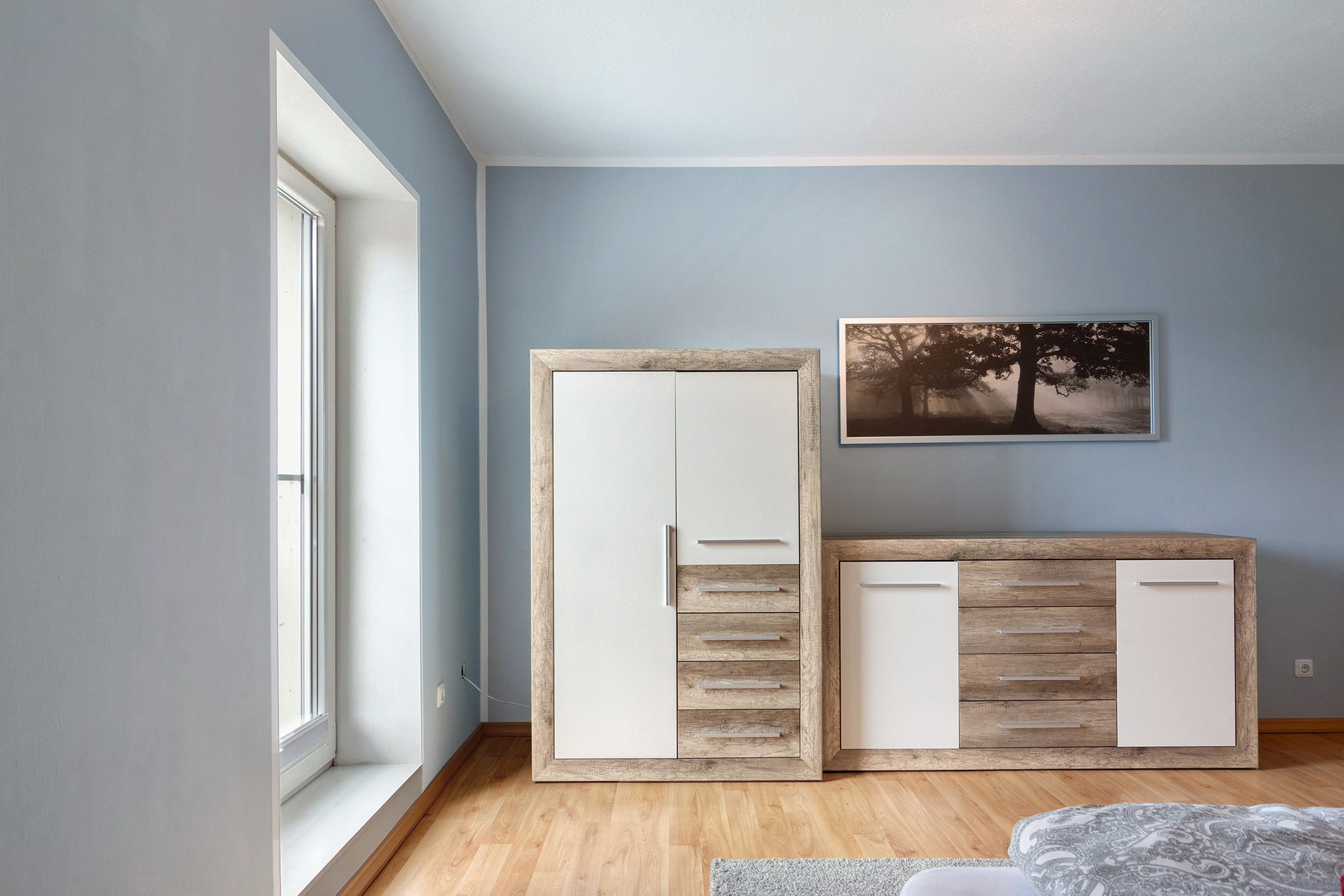 Een kamer met een grote kast, een klein kastje en een aan de muur hangend schilderij.