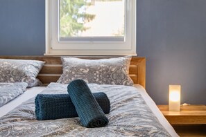 A bed with a patterned bedspread, two pillows, and a bedside lamp.