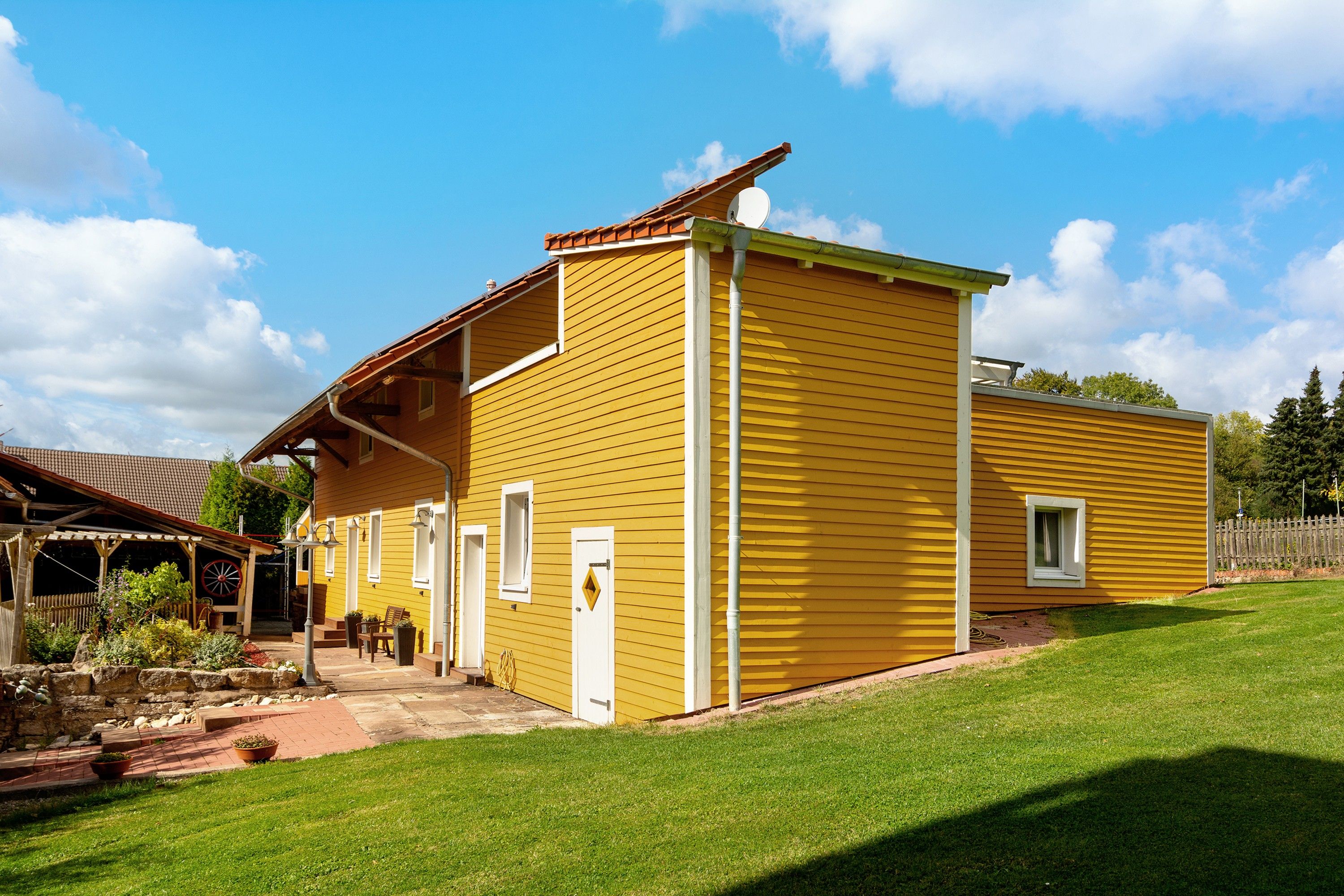 A yellow two-story house with a porch, a visible chimney, and a well-maintained lawn.