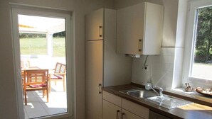 Een keuken met een spoelbak, kastjes en een raam.