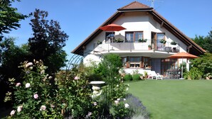 Ein zweistöckiges Haus mit Balkon, Rasen und einem Blumenbeet.