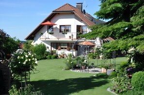 A two-story house with a balcony, a garden, and a patio area.