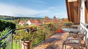 Ein Balkon mit Blick auf ein Dorf, einem Tisch und Stühlen.