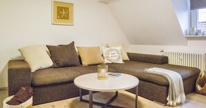 A cozy living room with a brown sofa, a white coffee table, and a framed picture on the wall.