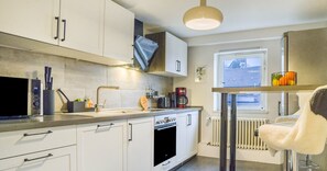 A modern kitchen with white cabinets, a built-in oven, a coffee maker, and a window with a view.