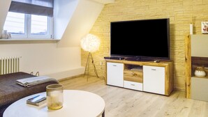 Un salon moderne avec un téléviseur à écran plat, des meubles en bois, une table ronde et un lampadaire.