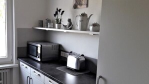 Une cuisine équipée d’un four à micro-ondes, d’un grille-pain et d’une étagère où sont disposés des objets décoratifs.