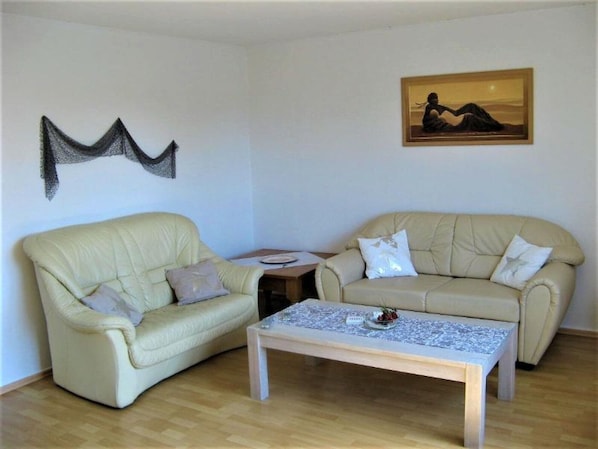 A living room with two sofas, a coffee table, a painting, and a wall decoration.