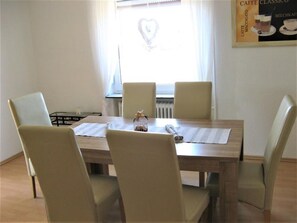 A dining table with four chairs, a small decorative item, and a window with a heart-shaped decoration.