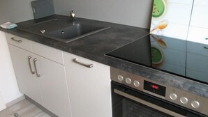 Une cuisine moderne dotée d’un évier à deux bacs, d’appareils électroménagers en acier inoxydable et d’un dosseret carrelé.