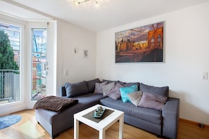 A modern living room with a gray sofa, a white coffee table, and a cityscape painting on the wall.