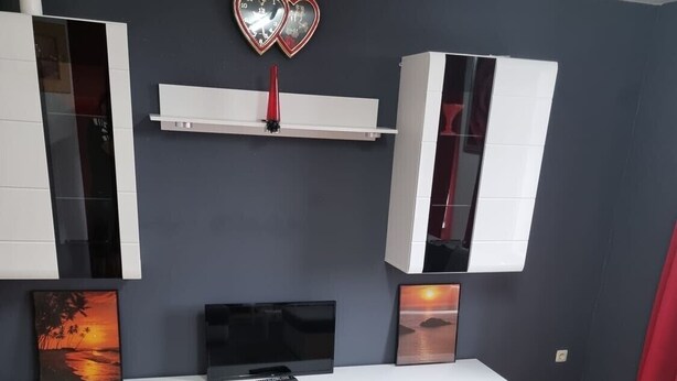 Ein modernes Wohnzimmer mit Flachbildfernseher, weißen Schränken und einer Couch.