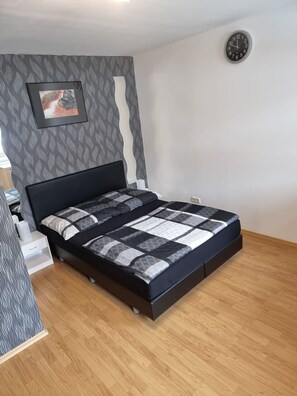 Une chambre à coucher avec un lit, une horloge et un tableau encadré accroché au mur.