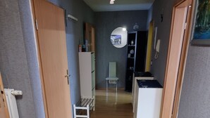 Ein Flur mit Holzboden, einem weißen Stuhl, einem kleinen Tisch und einem Schrank.