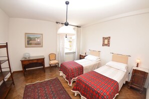 Cozy room with two single beds, a desk, and a chair, perfect for a comfortable stay.