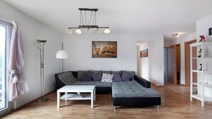 A modern living room with a sectional sofa, a white coffee table, a floor lamp, and artwork on the wall.