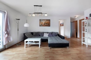 A modern living room with a sectional sofa, a white coffee table, a floor lamp, and artwork on the wall.